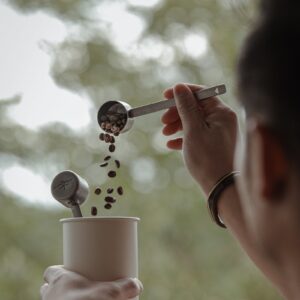 Mujer usando cuchara medidora de café para verter granos en una taza
