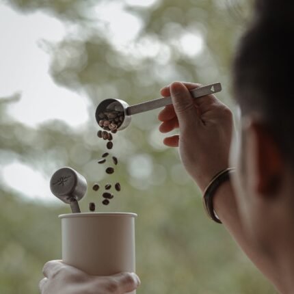 Mujer usando cuchara medidora de café para verter granos en una taza