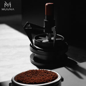Distribuidor de agujas para café modelo Mantis colocado sobre una mesa junto a un portafiltro con café molido.