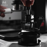 Barista utilizando un distribuidor de agujas para café de alta precisión para nivelar la molienda en el portafiltro.