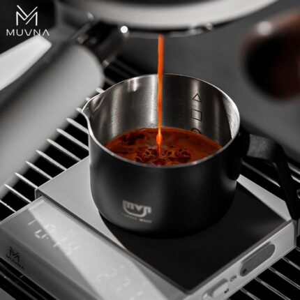 Taza para espresso 100 ml MUVNA, de acero inoxidable mate negro, en una sesión de preparación de café espresso, con el logo en la base.