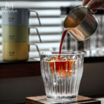 Taza para espresso 100 ml MUVNA, de acero inoxidable mate negro, en una sesión de preparación de café espresso.